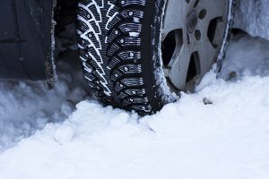 car, winter, people and vehicle concept - close-up of a car wheel in the snow